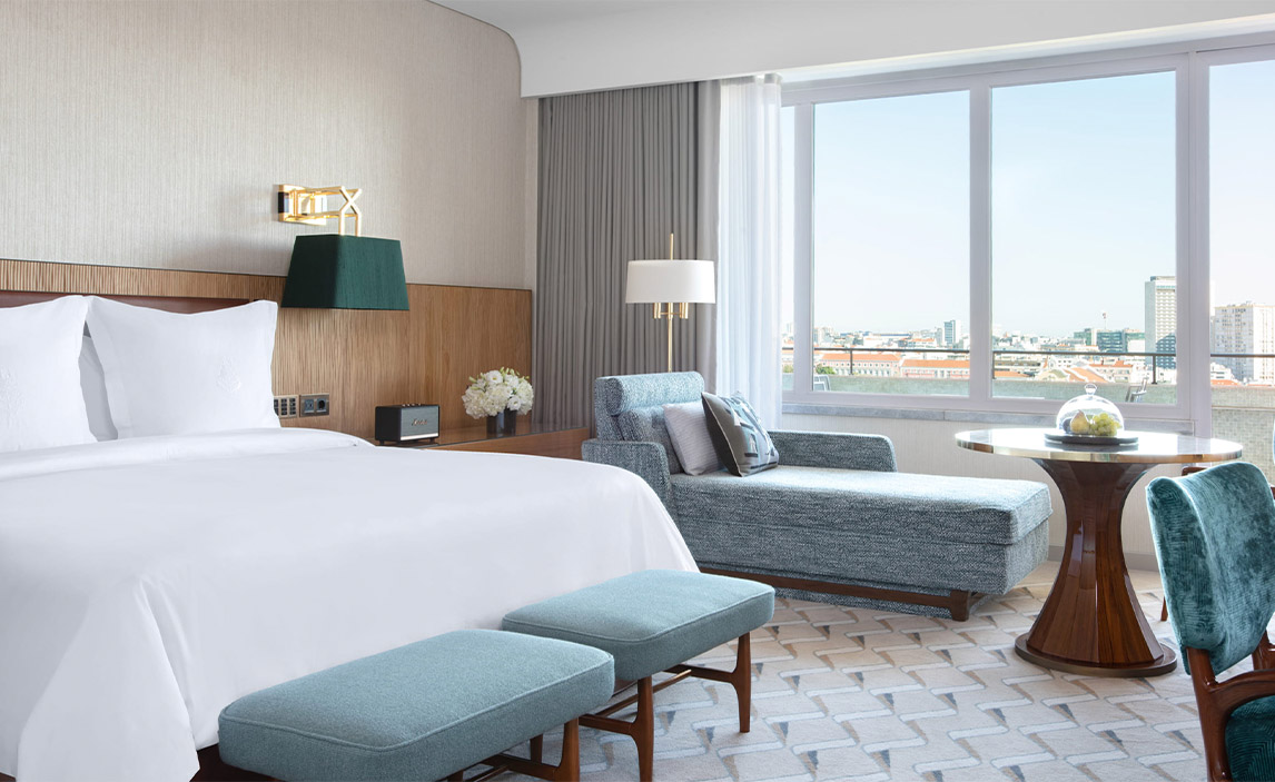 A hotel room with a view of Lisbon out of the window.
